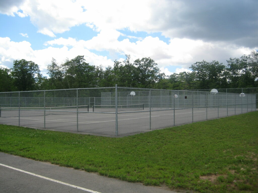 Outdoor basketball and tennis courts with chain-link fence.