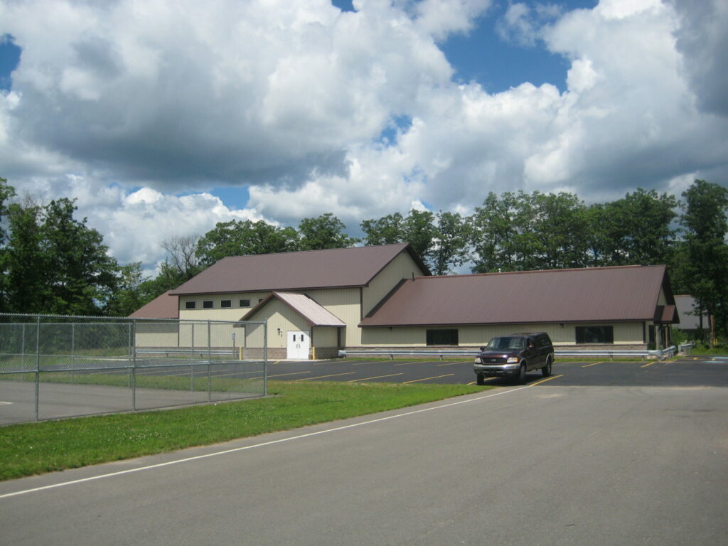 Modern building with parking lot and cloudy sky.